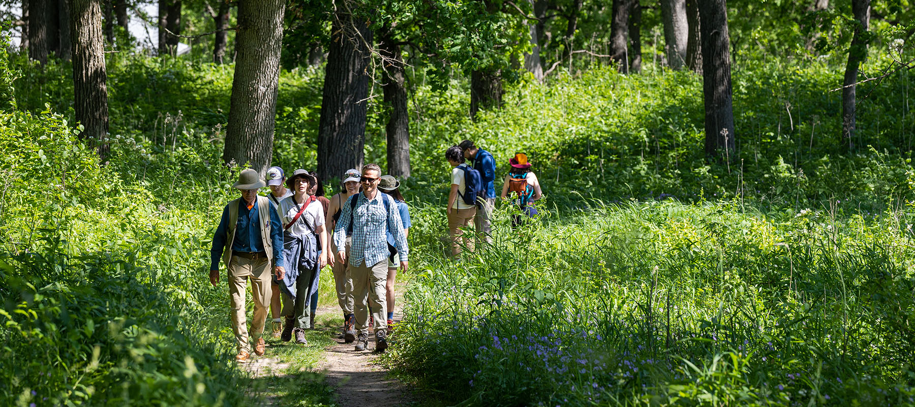 students and instructors walking on a path in the woods