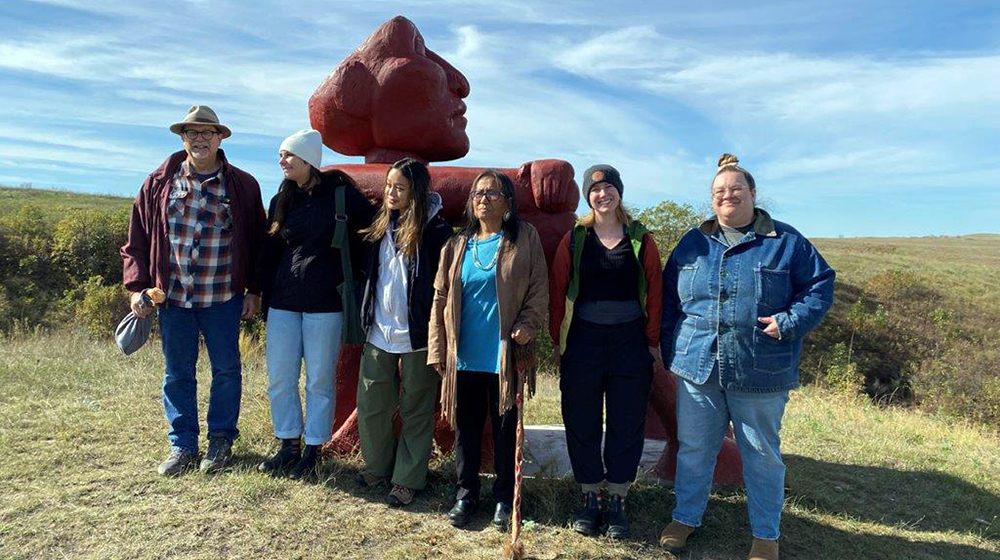 Students with the Not Afraid to Look sculpture of a seated figure 