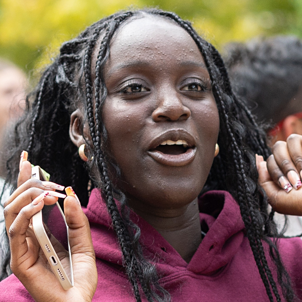A student holding her phone participates at an event during Welcome Week