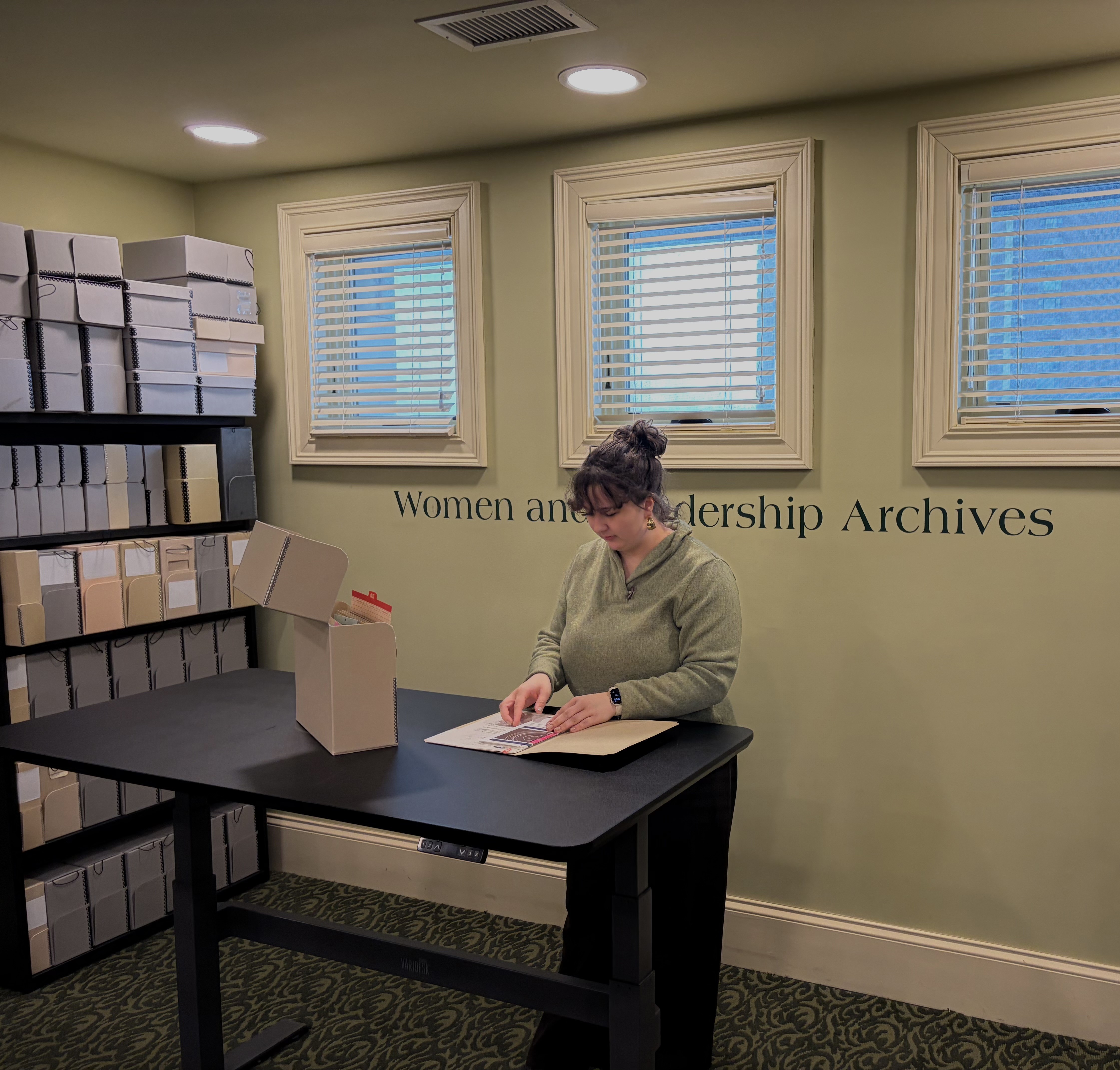 Researcher at the standing desk in the WLA reading room looking at materials in a folder Researcher at the standing desk in the WLA reading room looking at materials in a folder