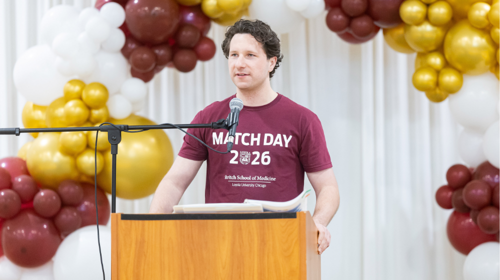 Matt Driscoll wearing a maroon Match Day t-shirt stands at a podium with maroon and gold balloons behind him Matt Driscoll wearing a maroon Match Day t-shirt stands at a podium with maroon and gold balloons behind him
