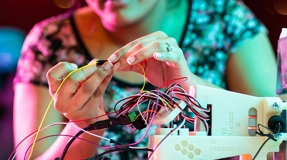 A person wiring some electronics in a lab. Closeup on the hands.
